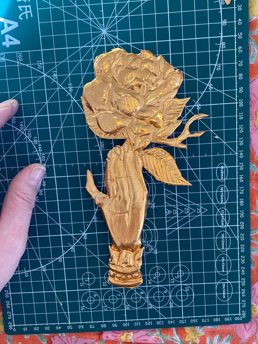 A golden embossed hand in the Victorian style on a green cutting board 